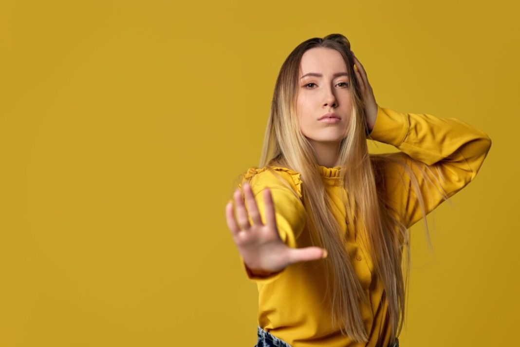 woman showing stop gesture on yellow background